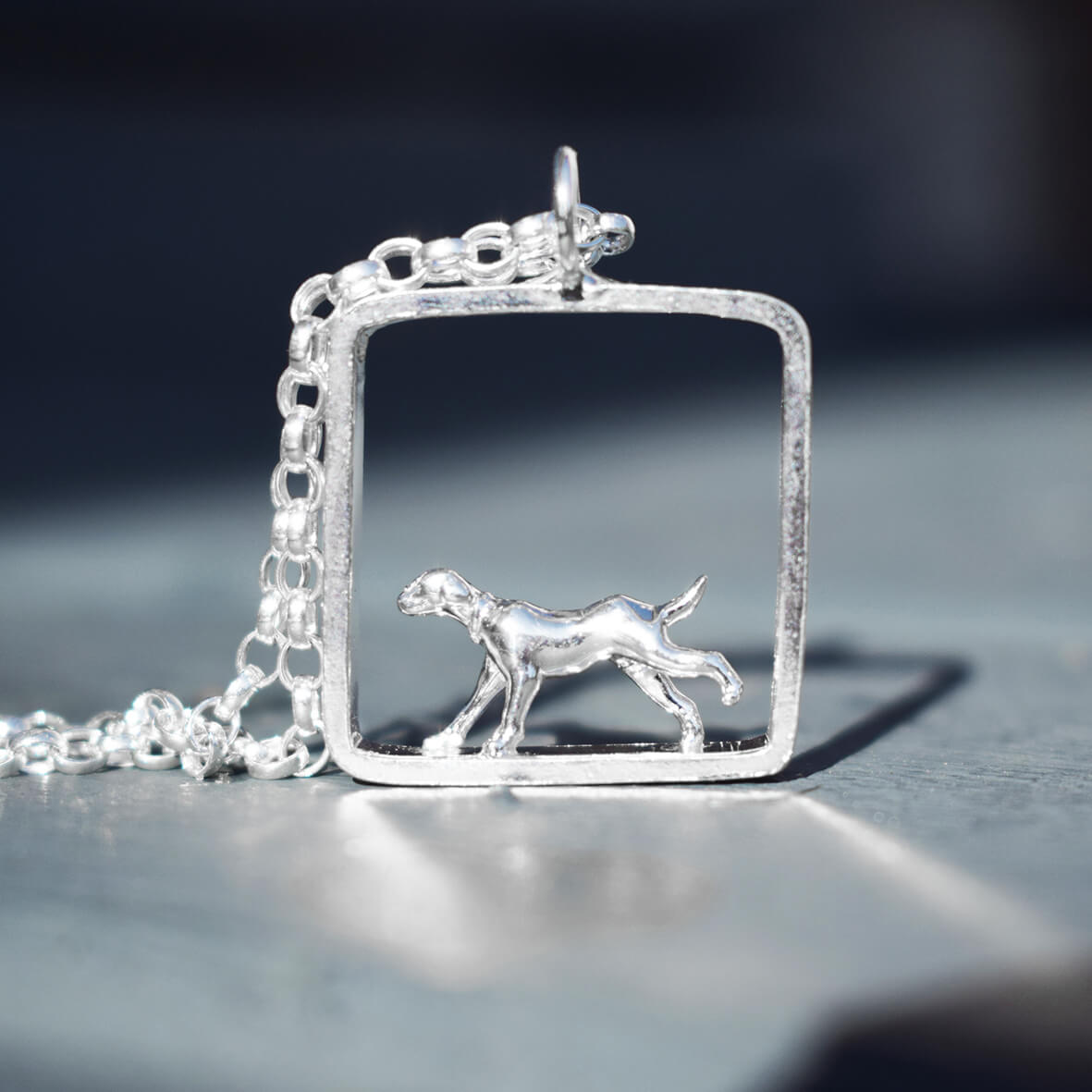 silver dog necklace with running hound design,elegant silver hound dog pendant in square frame,handcrafted silver necklace for dog lovers,
hound silhouette necklace for pet owners,minimalist silver dog jewellery UK,unique gift for dog lovers silver necklace,silver pendant featuring running dog in square,dog lover necklace handmade in silver,
hound-themed silver jewellery gift idea,
artisan silver necklace with dog design
